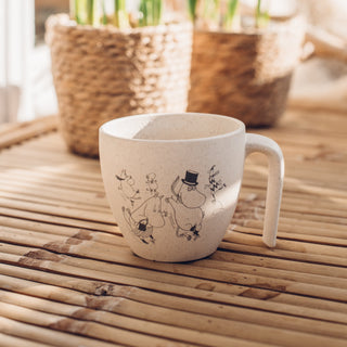 Muumit luistelee Muumimuki kevätauringossa parvekepöydällä.